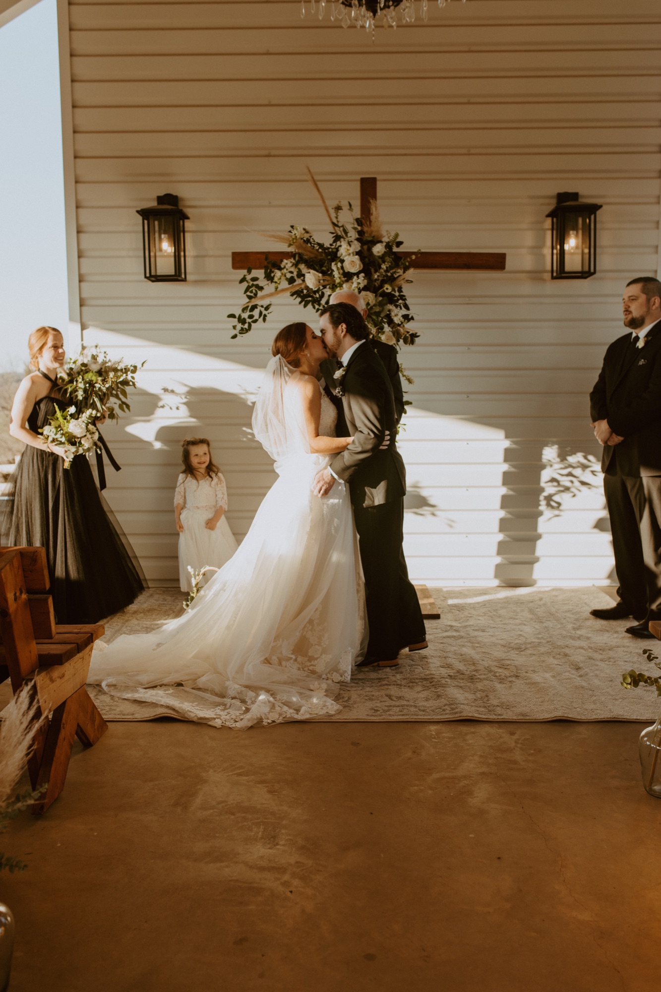 Stark white open-air chapel with a crystal chandelier and oak cross at Diamond H3 Ranch